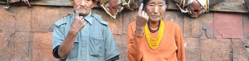 An old couple showing mark of indelible ink after casting their votes, at a polling...
